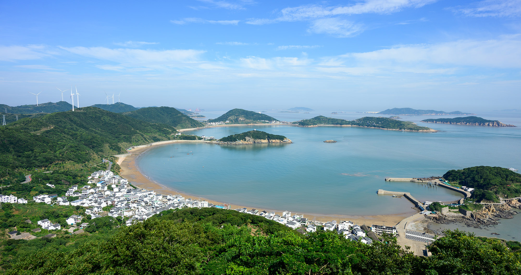 衢山岛海湾全景,远处可见风力发电机与白色村落